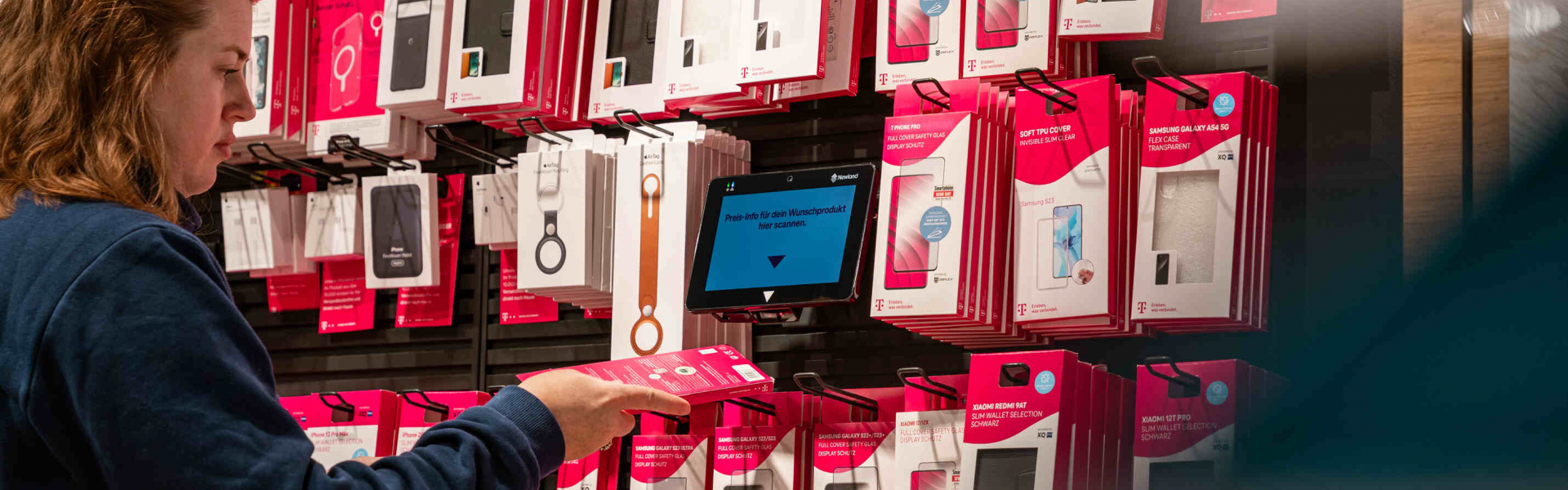 Image is a photograph of a person price checking their product using the Newland NQuire 750 Stingray Micro Kiosk with integrated barcode scanner.