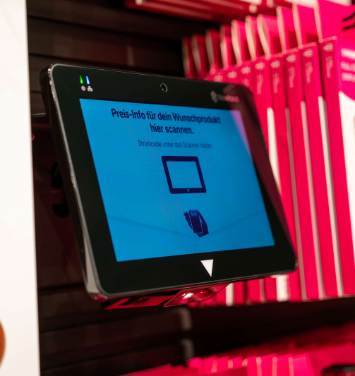 The NQuire 750 in Telekom Stores takes over price checking and labelling. The photograph displays the NQuire 750 Micro Kiosk Barcode scanner between the products.